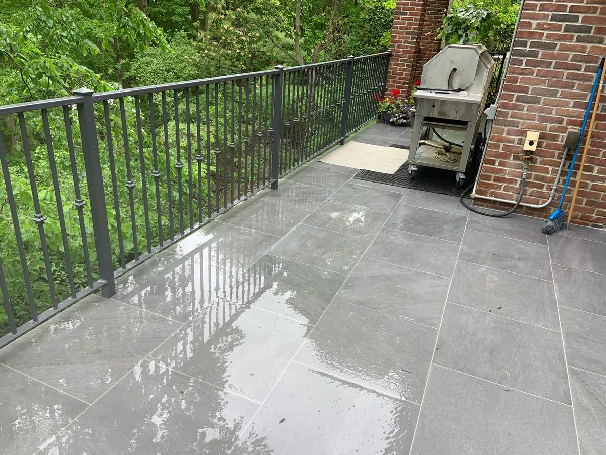 A wide rainy view of the balcony patio bordered by an iron railing.